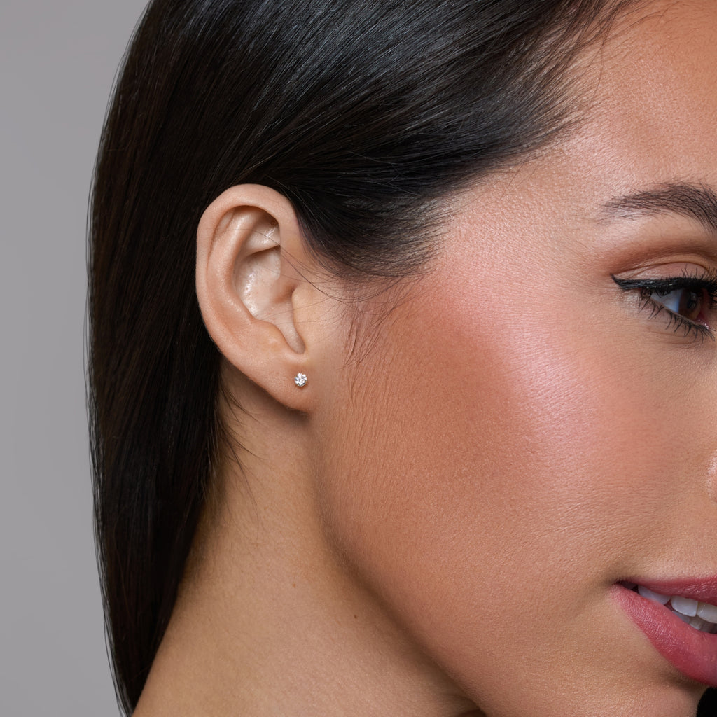 Gold stud earrings with clear gemstones on a white background