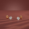 Pair of gold diamond stud earrings on a red background