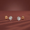 Gold diamond stud earrings on a red background