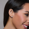Close-up of a woman wearing a diamond earring with a neutral background