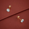 Gold stud earrings with clear gemstones on a red background