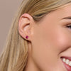 Close-up of a woman wearing july stud earrings with a neutral background