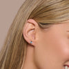 Close-up of a person wearing a diamond stud earring with a neutral background