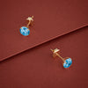 Gold earrings with blue gemstones on a red background