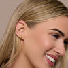 Close-up of a woman wearing a gold november birthstone earring with a beige background