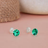 Silver stud earrings with green gemstones on a pink surface
