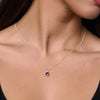 Necklace with a purple gemstone pendant on a person wearing a black top.