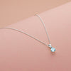 Silver necklace with a blue gemstone pendant on a beige background