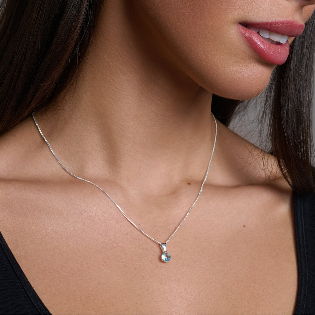 Silver necklace with a blue gemstone pendant on a white background