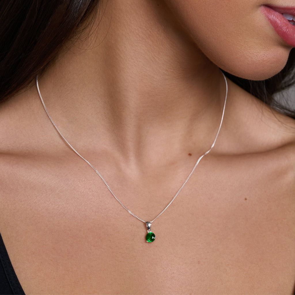 Silver necklace with a green gemstone pendant on a white background