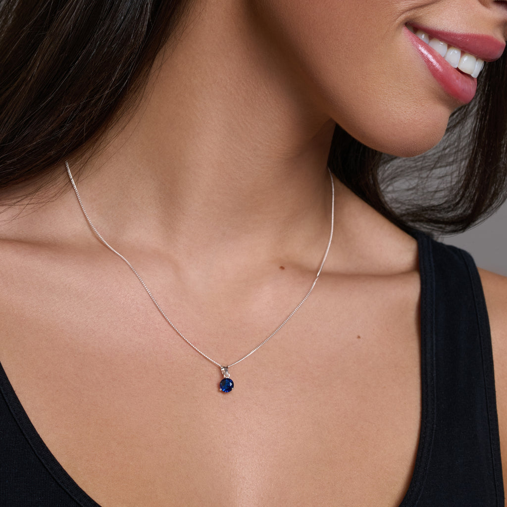 Silver necklace with a blue gemstone pendant on a white background