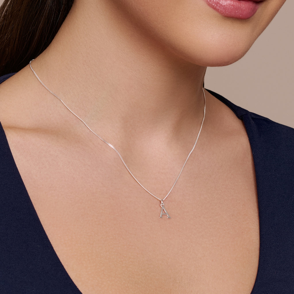 Silver necklace with a letter 'A' pendant on a white background