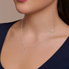 Silver necklace with a 'H' pendant on a model wearing a navy top.