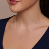 Silver necklace with a pendant worn by a person against a neutral background