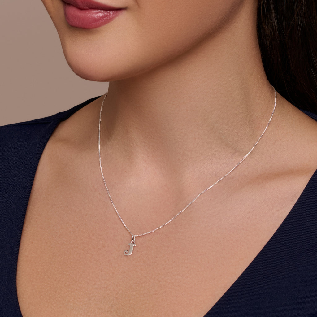 A sterling silver necklace with a large letter 'J' pendant on a chain.