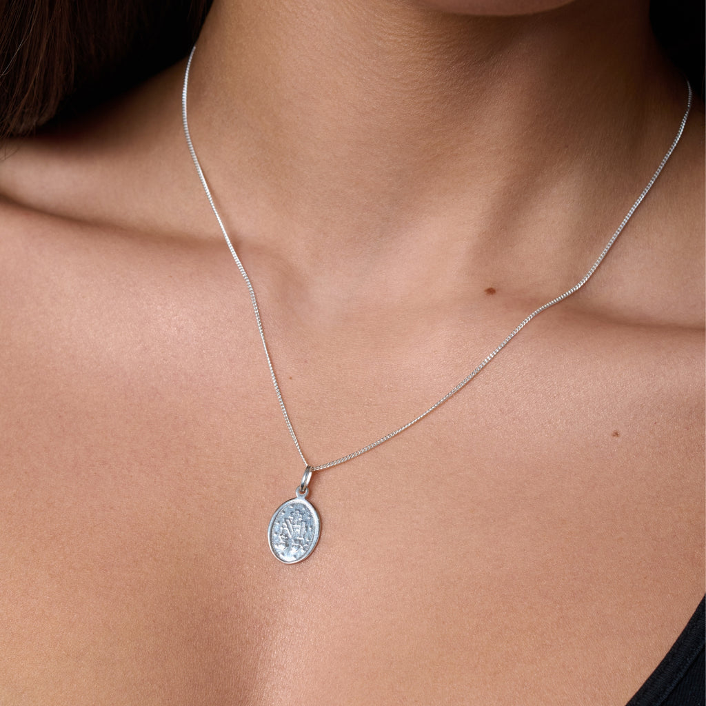 Two silver religious pendants on chains against a white background