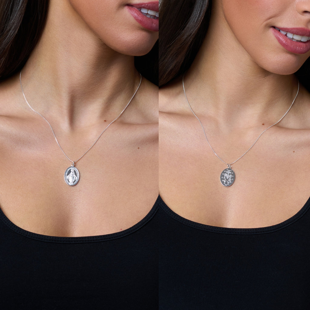 Two silver religious medallions on chains against a white background